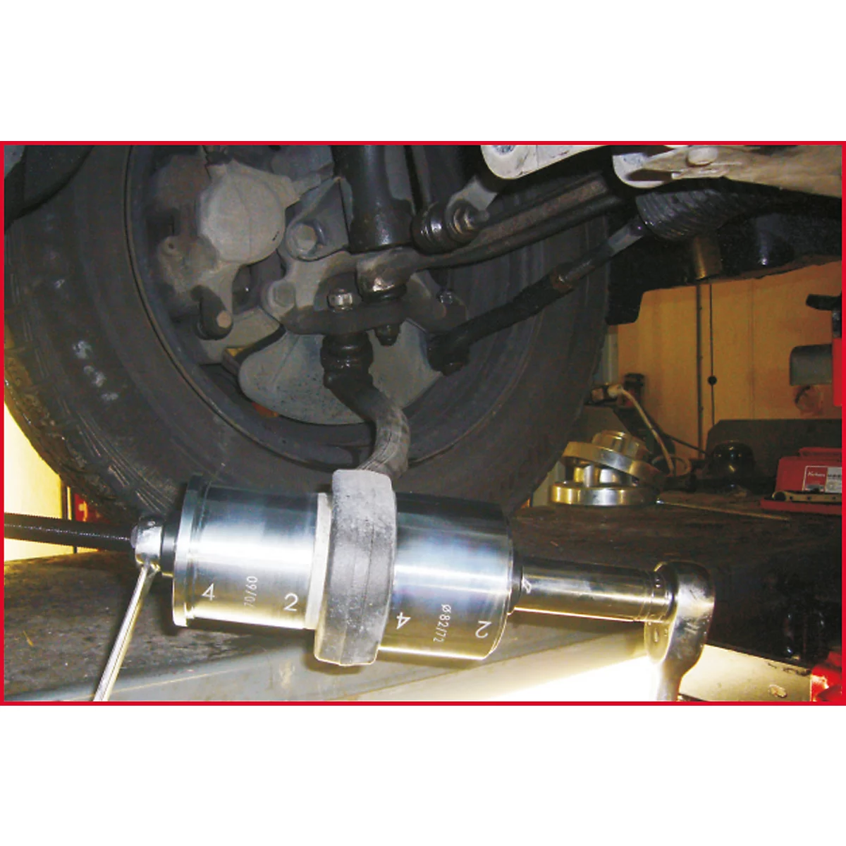 Nahaufnahme eines Werkzeugs, das an einem Autoreifen montiert ist. Die Reifen sind schwarz und stehen auf einer Hebebühne. Die Werkzeuge sind aus Metall.